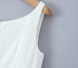 Detail of white summer dress with floral embroidery and geometric hollow mesh texture