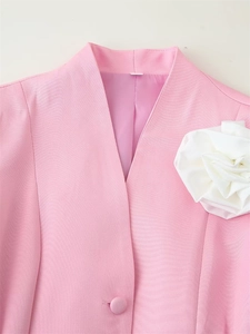 Détail du blazer rose avec fleur 3D blanche appliquée et texture de tissu doux