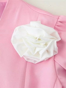 Détail d'une grande fleur en tissu 3D blanc sur une veste rose pâle à manches courtes
