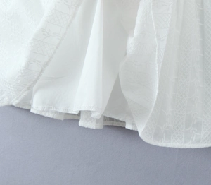 Detail view of white embroidered floral hemline with sheer mesh and solid lining