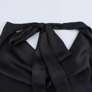 Close-up of black satin halter top featuring a elegant back bow tie and silk texture