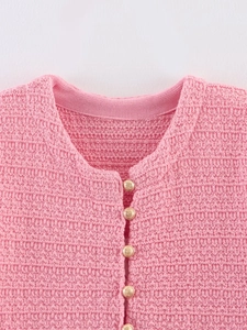 Gros plan d'un cardigan en tricot rose avec boutons dorés élégants et col rond
