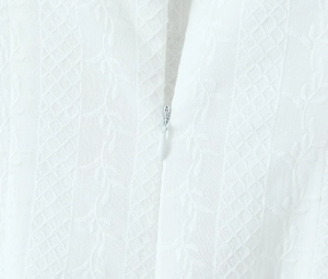 Close-up of white dress fabric with floral embroidery, hollow texture and hidden zipper
