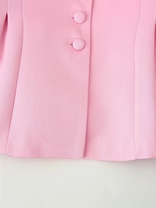 Détail du tissu d'un blazer rose montrant des coutures fines et des boutons recouverts