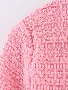 Détail de la couture d'épaule et des motifs de tissage sur le haut en tricot rose