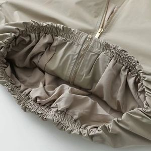 Detail of the elastic waistband and golden metal zipper on this stylish khaki jacket