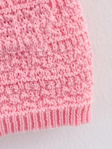 Détail de maille rose avec un motif crochet texturé et une finition de bord-côte serrée