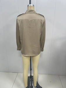 Detail view of champagne gold satin shirt featuring shoulder straps and glossy fabric