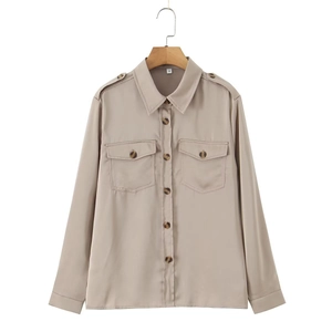 Detail of khaki satin shirt featuring buttoned flap pockets and epaulette shoulder straps