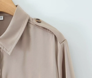 Detail view of khaki satin shirt featuring classic collar and buttoned epaulettes