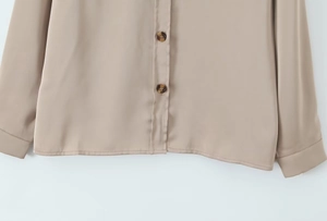 Detail of khaki satin blouse showing premium fabric texture and tortoiseshell buttons