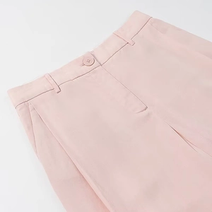 Detail view of pink wide-leg trousers showing waist button, zipper, and textured fabric