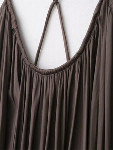Detailed macro view of dark brown pleated fabric with delicate straps and shirred neckline
