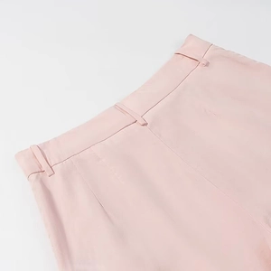 Detail of light pink high waist pants featuring belt loops and soft pleated texture