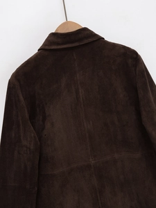 Close-up of the dark brown suede texture and central stitching on the back of the jacket