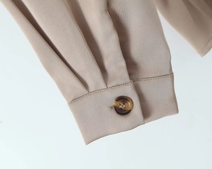 Detail of the pleated cuff and marble button on this apricot satin long sleeve shirt