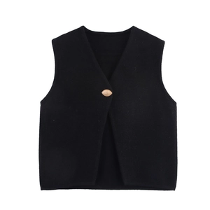 Close-up of black knit vest featuring deep V-neck and a single golden oval button detail