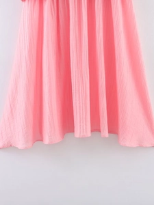 Détail de l'ourlet d'une jupe plissée rose vif avec textures verticales et coutures nettes