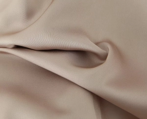 Close-up of champagne satin fabric showing silky texture and luxurious glossy finish