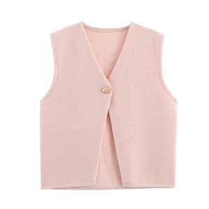Detail of light pink knitted vest featuring V-neckline and decorative gold button