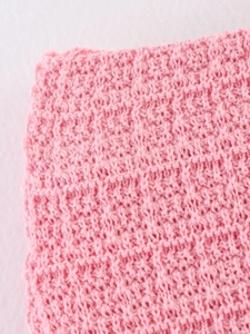 Gros plan sur un tissu tricoté rose avec une texture douce à points croisés pour l'été