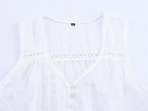 Close-up detail of white V-neck blouse featuring delicate lace embroidery and buttons