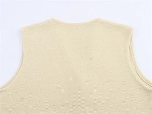 Detailed close-up of beige knitted vest showing collar stitching and fine fabric texture