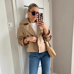 Classic khaki short double-breasted trench coat with wide lapels and cuff straps