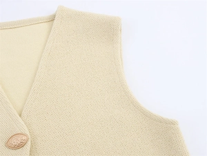 Close-up of a beige knitted vest featuring a vintage gold embossed metal button detail