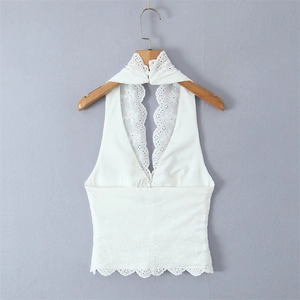 Detailed view of white halter top featuring intricate lace floral embroidery and back buttons