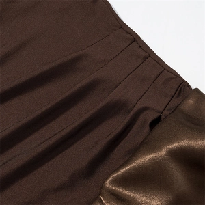 Detail of dark brown dress showing matte ribbed fabric stitched with glossy satin material