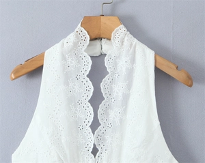 Detail view of white lace halter top featuring delicate floral embroidery and scalloped edges