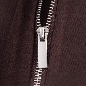 Détail de chemise en velours marron foncé avec fermeture éclair argentée et texture douce