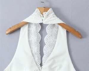 Close-up of white halter neck with intricate floral lace embroidery and button detail