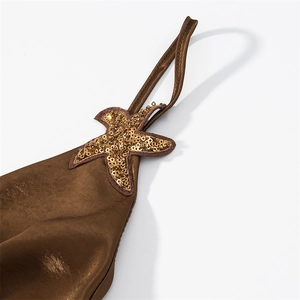 Detailed macro view of gold starfish sequin patch on brown satin dress strap