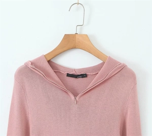 Detail of pink knitted hoodie showing zipper neckline and fine fabric texture on a hanger