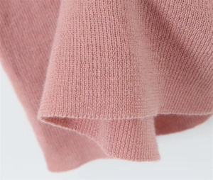 Macro detail of soft light pink knit fabric showing fine texture and smooth stitching