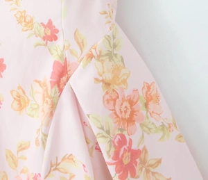 Detailed macro shot of floral print fabric and sewing seams on light pink dress
