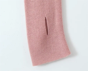 Macro detail of pink knit sweater featuring functional thumbhole cuffs and rib texture