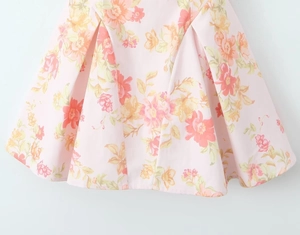 Detailed view of pink floral print dress hem with elegant pleats and rich patterns