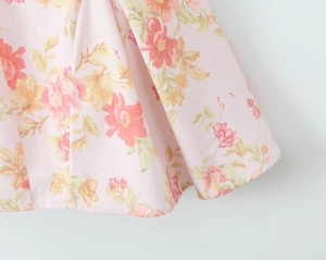 Detailed macro view of light pink floral chiffon fabric with vibrant orange flower print