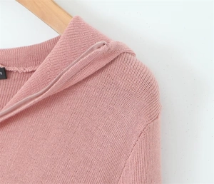 Detail of light pink knit sweater featuring silver half-zip collar and soft ribbed texture