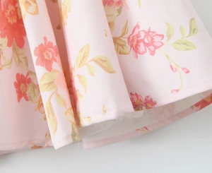 Close-up of pink floral dress hem showing detailed stitching and soft woven fabric texture