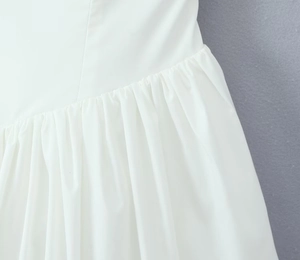 Close-up of white summer dress featuring elegant ruffle pleats and smooth fabric texture