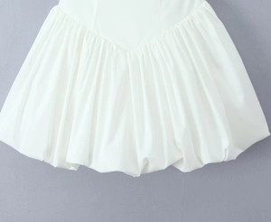 Close-up of white bubble hem skirt with pleated details and crisp woven fabric texture