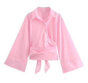 Detail of pink poplin shirt featuring wrap waist tie and elegant flared sleeves design