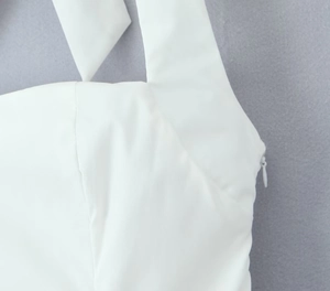 Detail view of the halter neckline and white invisible side zipper on a summer dress