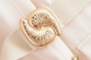 Dettaglio di elegante fibbia a spirale dorata con trama radiale su un abito rosa