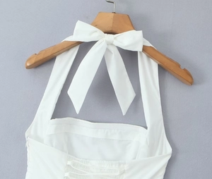 Detail of white halter neck dress with large bow tie and open back crisscross straps