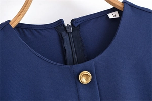 Dettaglio collo rotondo e bottone dorato su abito blu navy con zip posteriore invisibile